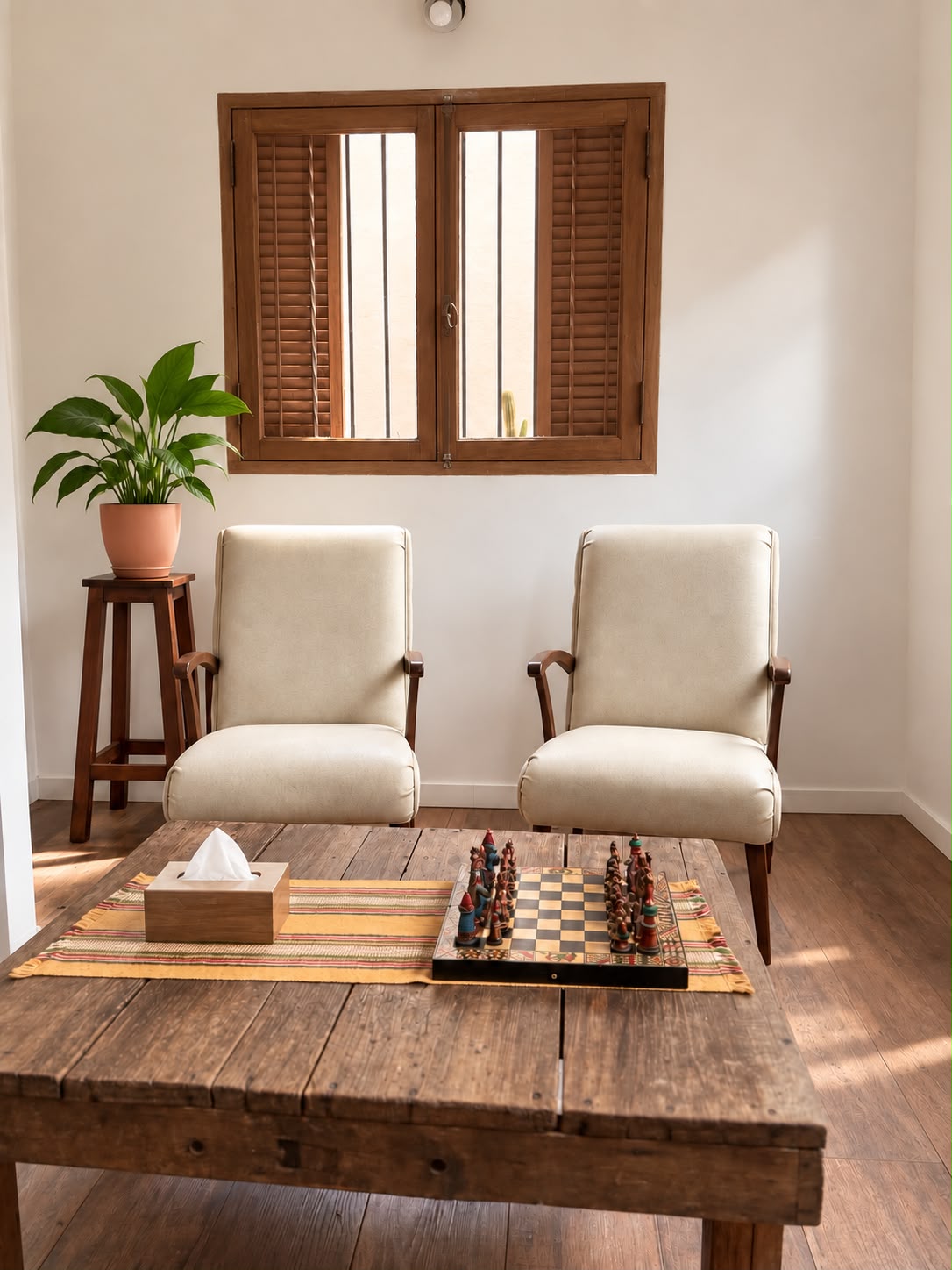 Consultorio de Villa Ballester, con dos sillones, mesa de madera y ventana conservada